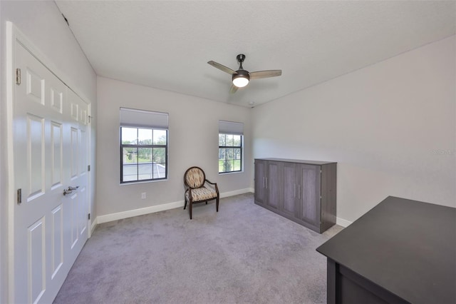 living area featuring carpet flooring, baseboards, and ceiling fan