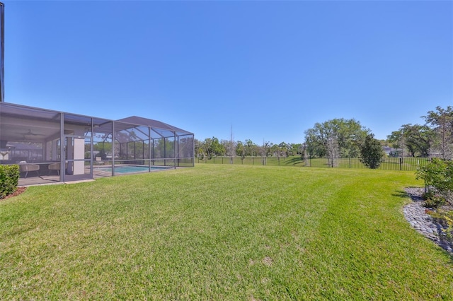 view of yard with glass enclosure, an outdoor pool, and fence