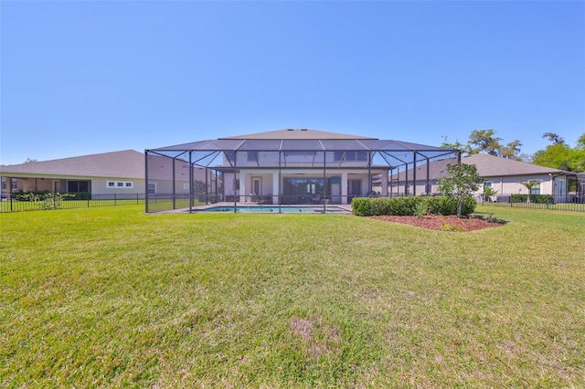 rear view of house featuring a lanai, a yard, and fence