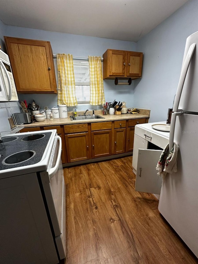 kitchen featuring dark wood finished floors, light countertops, brown cabinetry, white appliances, and a sink