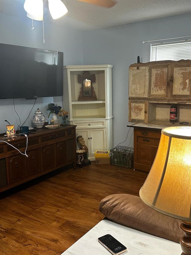 living area with a textured ceiling, wood finished floors, and a ceiling fan