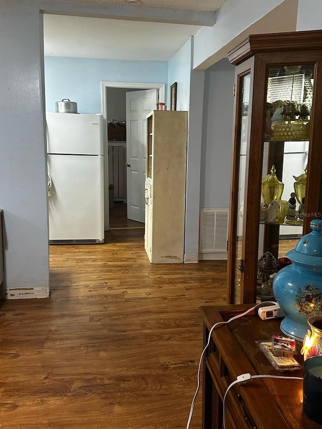 interior space featuring visible vents, beam ceiling, wood finished floors, and freestanding refrigerator