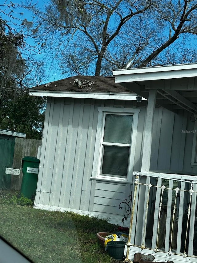 view of home's exterior featuring board and batten siding, a shingled roof, and fence