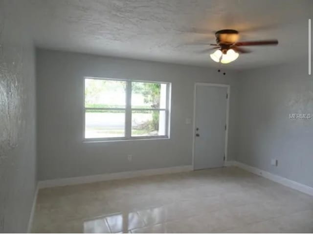 unfurnished room with ceiling fan and baseboards