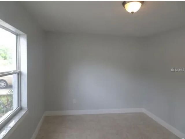 spare room with a wealth of natural light and baseboards