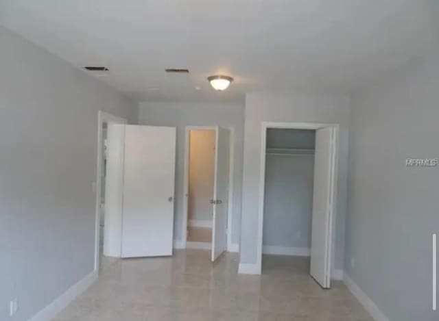 unfurnished bedroom with a closet, baseboards, and visible vents