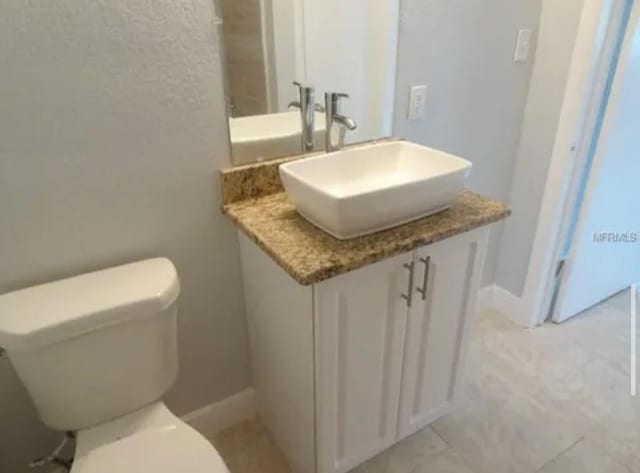 bathroom featuring baseboards, toilet, and vanity