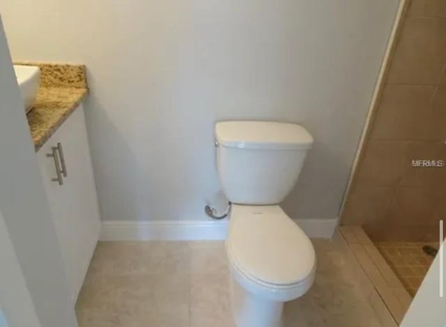 bathroom with vanity, baseboards, a tile shower, tile patterned flooring, and toilet