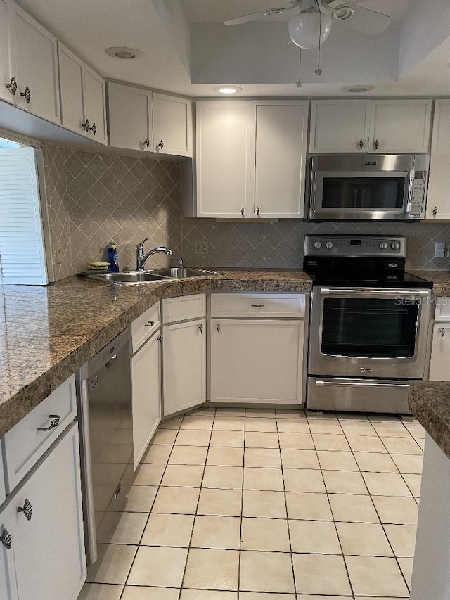 kitchen featuring tasteful backsplash, ceiling fan, light tile patterned floors, stainless steel appliances, and a sink