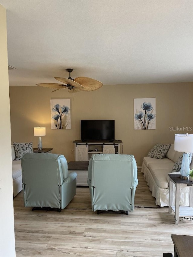 living room with a textured ceiling, wood finished floors, and a ceiling fan