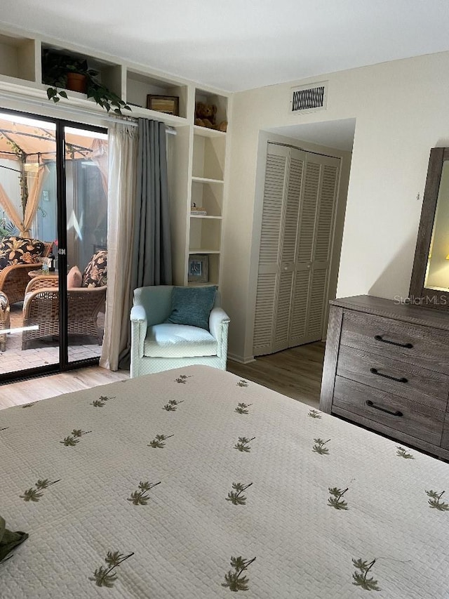 bedroom with visible vents, a closet, wood finished floors, and access to outside