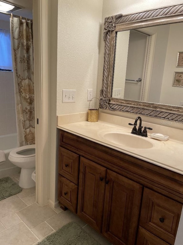 bathroom with tile patterned floors, toilet, vanity, and a textured wall