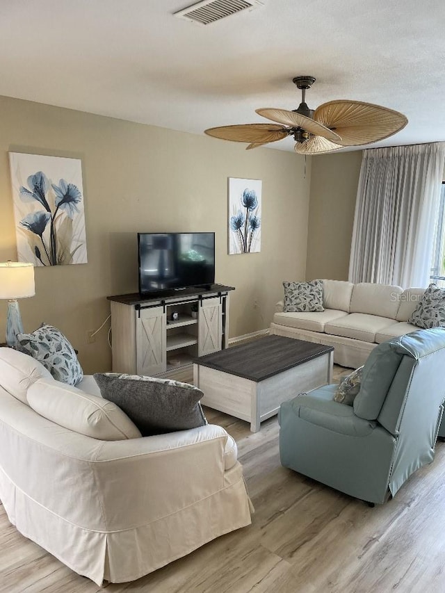 living area with light wood finished floors, visible vents, and ceiling fan