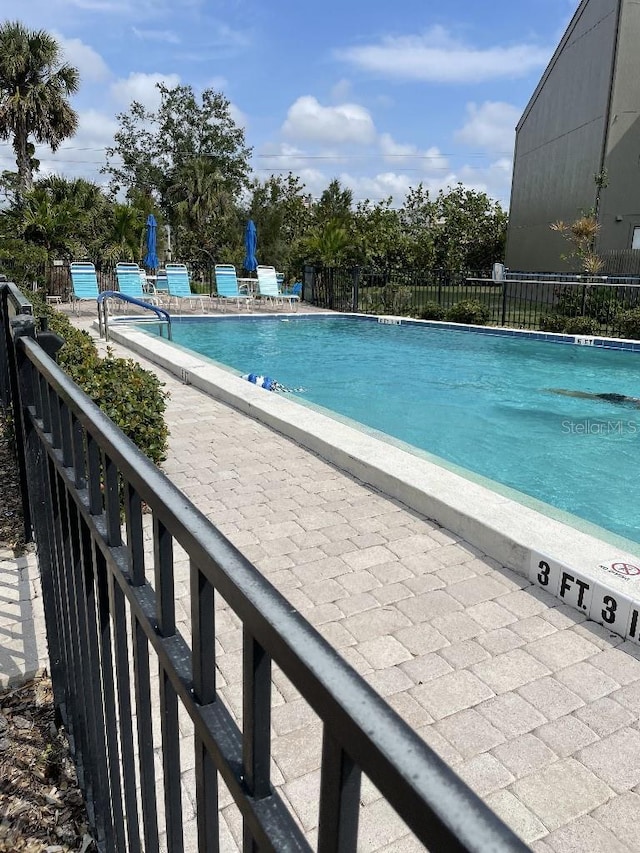 pool with a patio area and fence