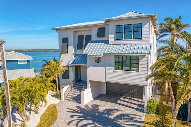 raised beach house featuring stucco siding, driveway, metal roof, and a standing seam roof