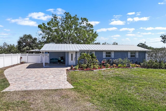 back of house with stucco siding, a lawn, decorative driveway, and an attached carport