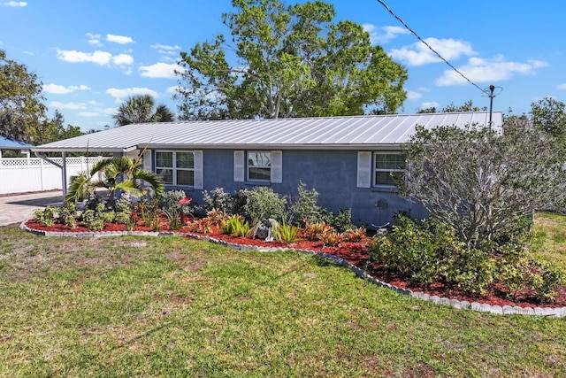 ranch-style house with stucco siding, metal roof, a front yard, and fence