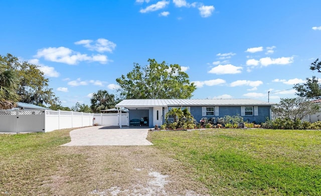 rear view of property featuring driveway, a standing seam roof, fence, a yard, and metal roof