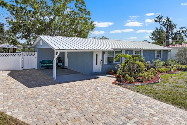 view of front of house with fence, stucco siding, metal roof, a standing seam roof, and a gate