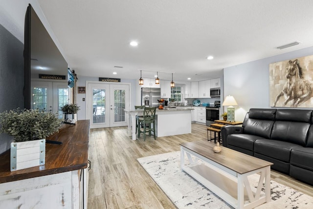 living room with visible vents, recessed lighting, french doors, and light wood-style floors