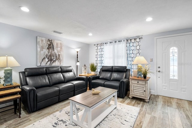 living area with a wealth of natural light, visible vents, light wood-style floors, and recessed lighting