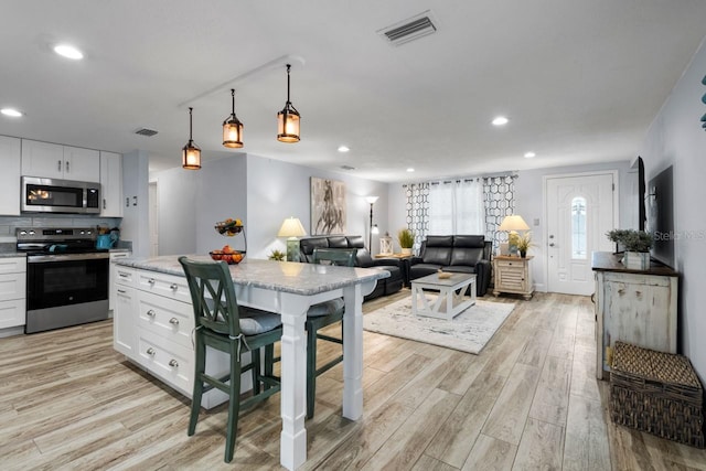 kitchen with white cabinets, visible vents, light wood finished floors, and stainless steel appliances