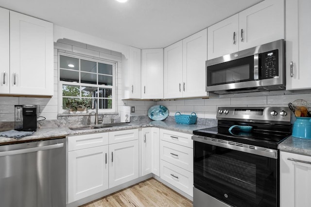 kitchen featuring white cabinetry, tasteful backsplash, appliances with stainless steel finishes, and a sink