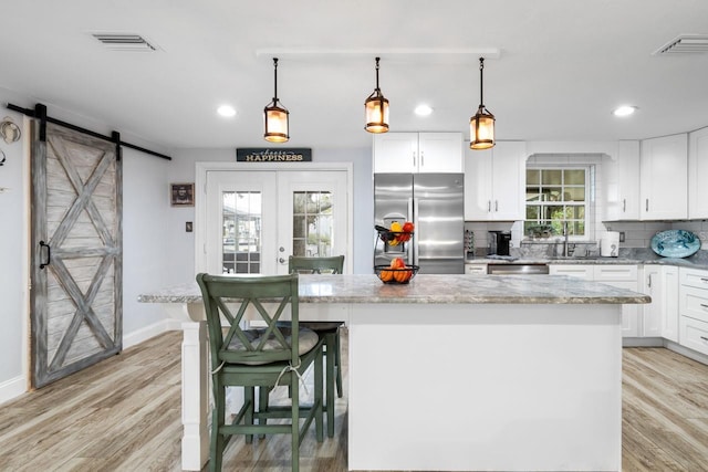 kitchen with visible vents, a center island, freestanding refrigerator, and a barn door