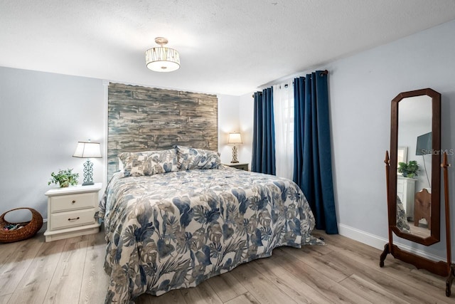 bedroom with baseboards, a textured ceiling, and wood finished floors