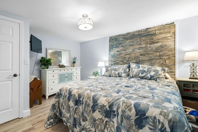 bedroom featuring an accent wall and light wood finished floors