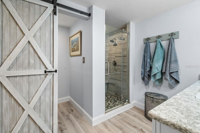 full bath with baseboards, wood finished floors, and a shower stall