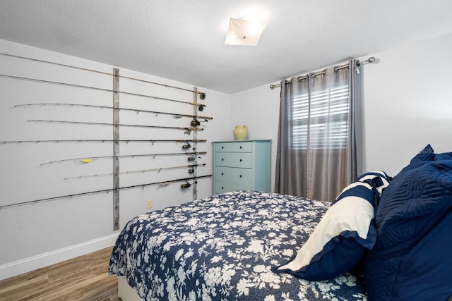 bedroom featuring wood finished floors, baseboards, and a textured ceiling