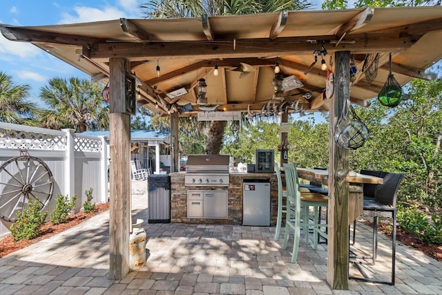 view of patio / terrace with a gazebo, an outdoor kitchen, a grill, and fence