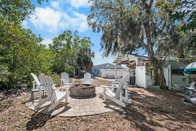 exterior space with fence, an outdoor structure, a storage unit, a fire pit, and a patio area