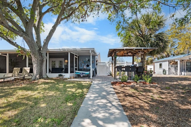 exterior space featuring a front lawn, fence, a sunroom, and a patio area