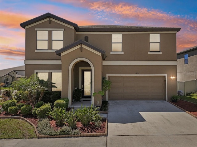 traditional home featuring a garage, driveway, and stucco siding