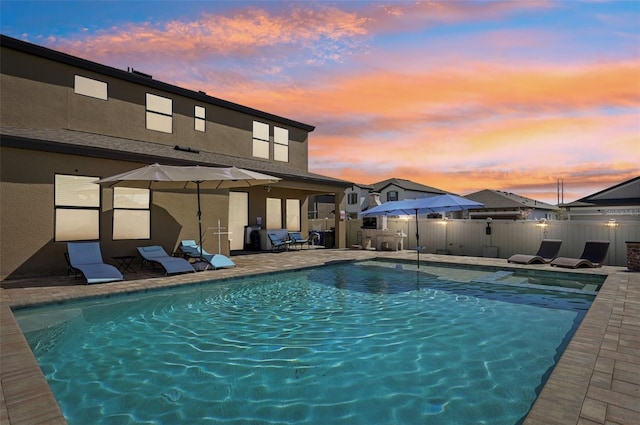 pool at dusk with a fenced in pool, a patio, and fence