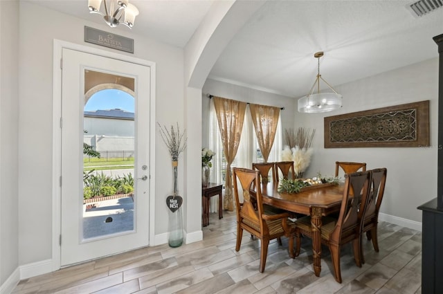 dining room featuring arched walkways, visible vents, and baseboards