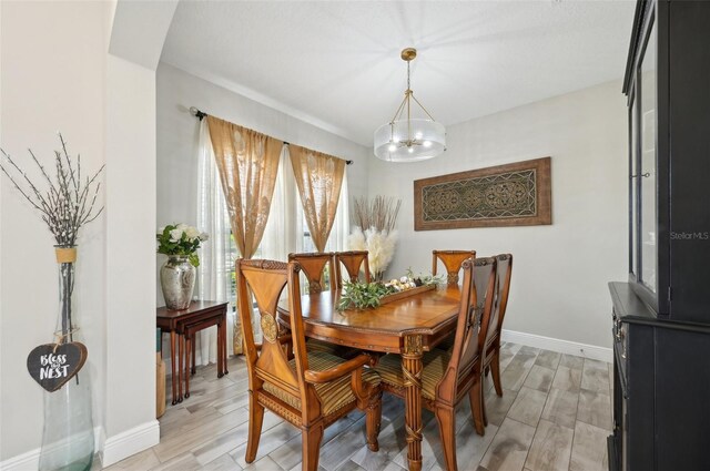 dining space with a chandelier, baseboards, and light wood-style flooring