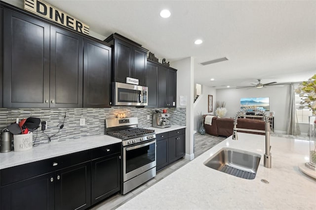 kitchen featuring a sink, tasteful backsplash, open floor plan, stainless steel appliances, and dark cabinets