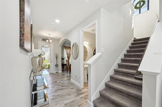 interior space featuring baseboards, stairs, recessed lighting, light wood-style flooring, and an inviting chandelier