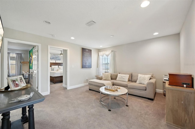 living area with recessed lighting, visible vents, baseboards, and light colored carpet