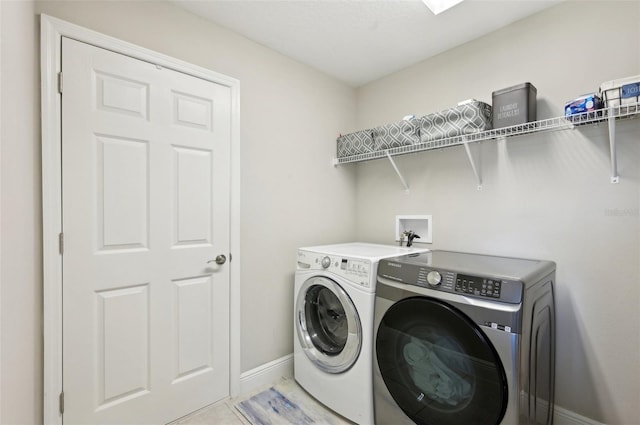 clothes washing area with light tile patterned flooring, laundry area, washing machine and dryer, and baseboards