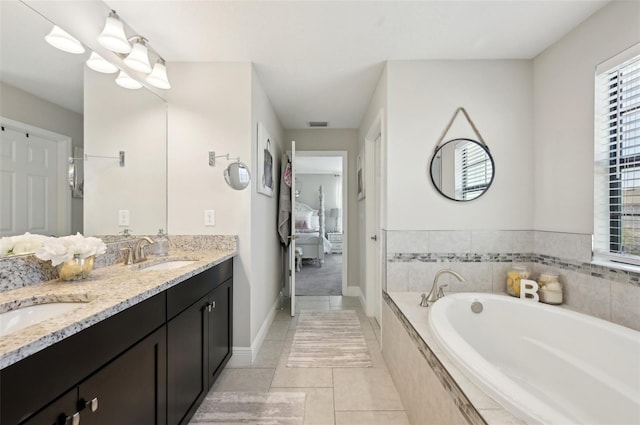 ensuite bathroom with ensuite bath, a bath, double vanity, and a sink