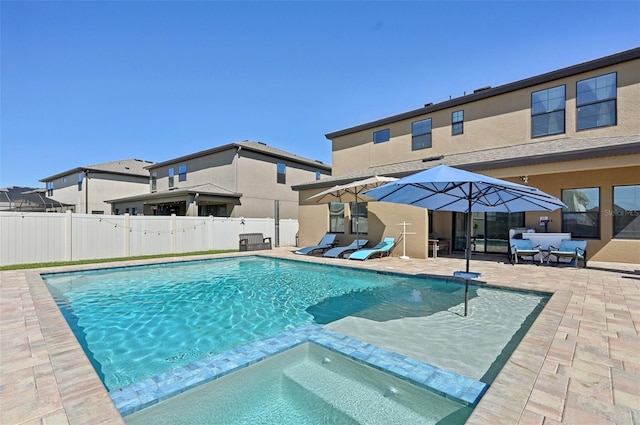 view of swimming pool with fence, a pool with connected hot tub, and a patio area