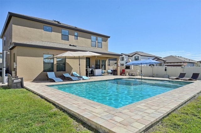 rear view of property featuring a patio area, stucco siding, a fenced in pool, and fence