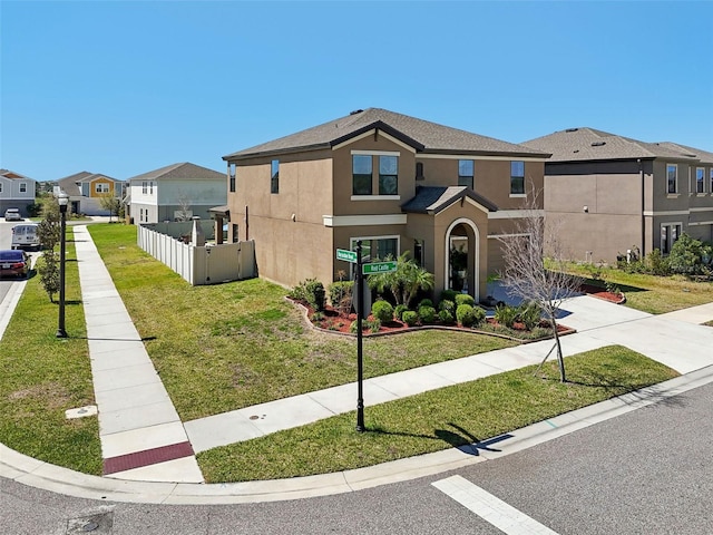 view of front of property with stucco siding, a residential view, a front lawn, and fence