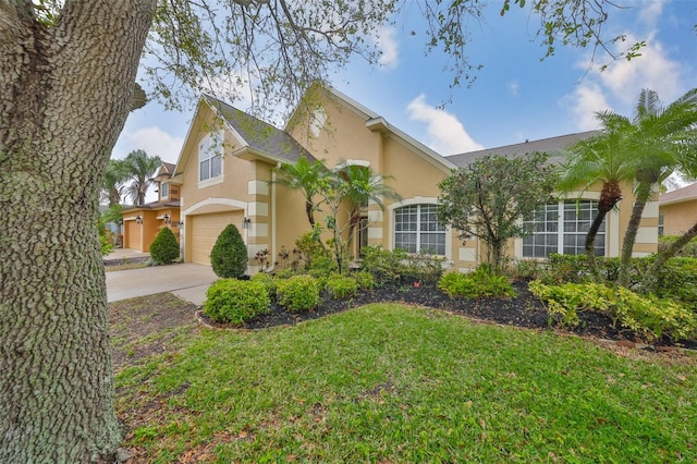 view of front of house with stucco siding, an attached garage, concrete driveway, and a front lawn