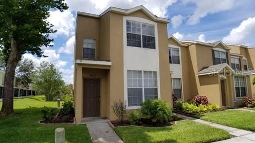 townhome / multi-family property featuring stucco siding and a front lawn