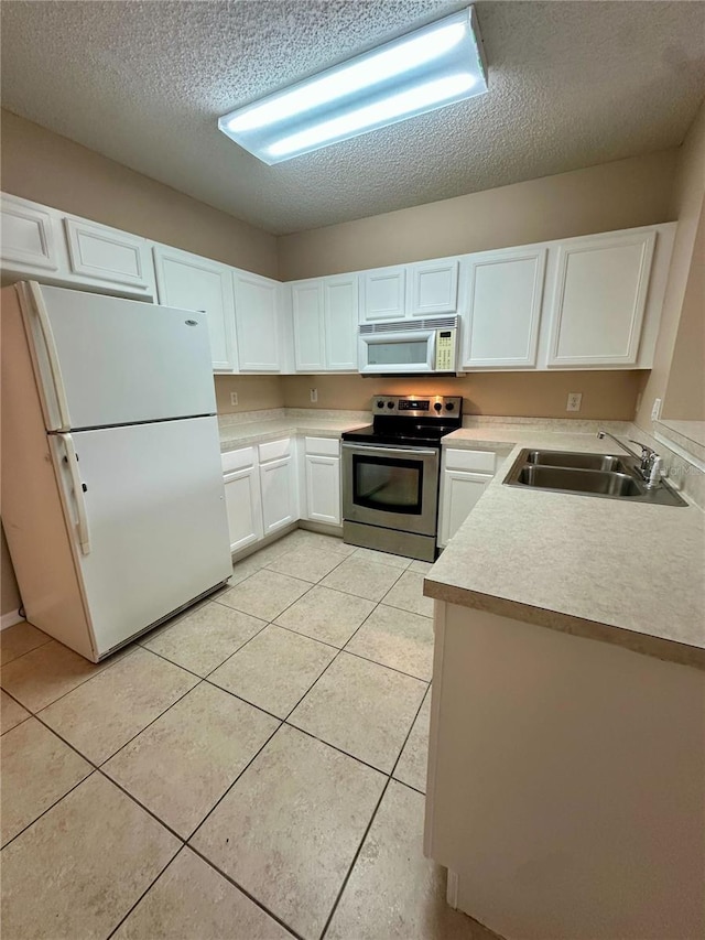 kitchen with light tile patterned flooring, white appliances, white cabinetry, and a sink